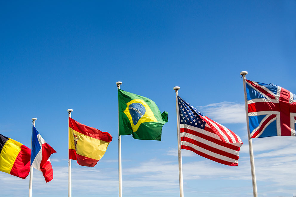 Hoisted flags waving in the wind with a blue and bright sky at the background